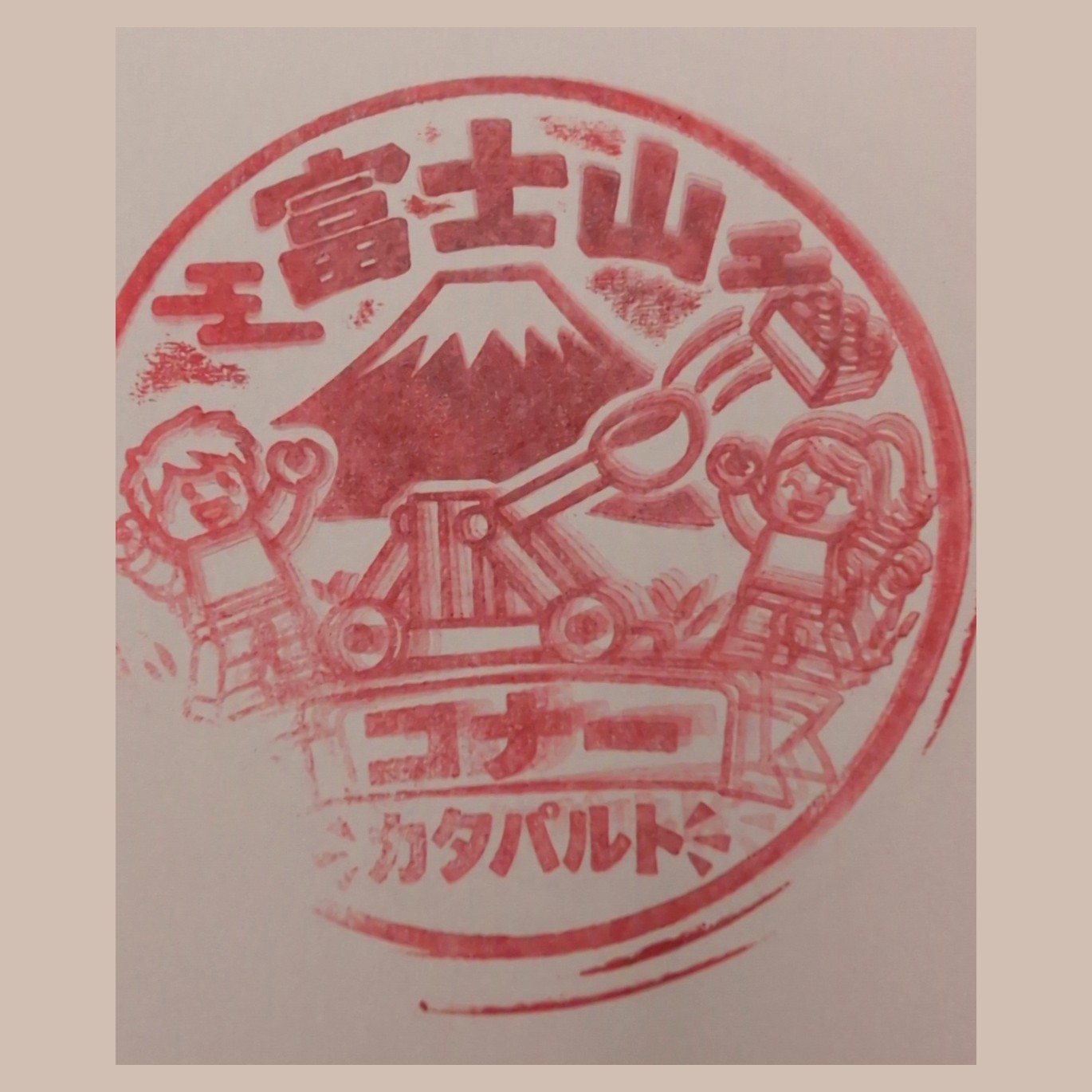 Ink impression of a stamp showing Mount Fuji, a catapult and two minifigures